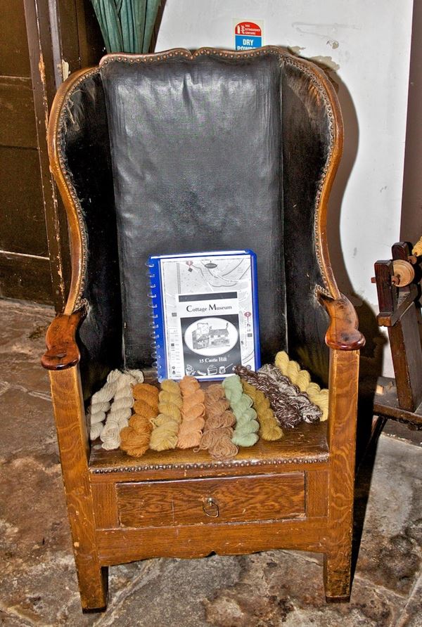 Photo of wingbacked wooden chair with leather upholstery on the back.